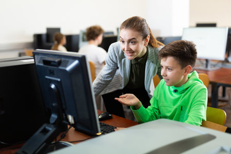 Teacher together with students conduct lesson on computer educationの写真素材