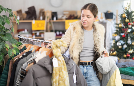 Woman choosing a down jacket in a Christmas shopの写真素材