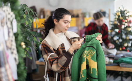 Armenian woman stands in a shop decorated for Christmas and picks up a warm sweaterの写真素材