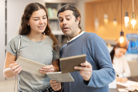 Couple of man and woman choosing sample of laminate flooring in hardware storeの写真素材