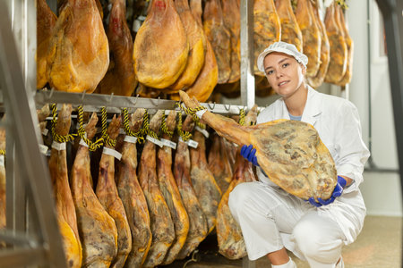 young specialist keeps a large jamon in the workshopの写真素材