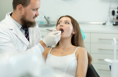 Male dentist checking the teeth of a woman in the officeの写真素材