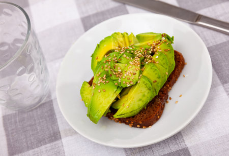 Sandwich with rye bread, sliced avocado and sesameの写真素材