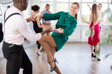 Woman and man dancing foxtrot in pair during group dance partyの写真素材