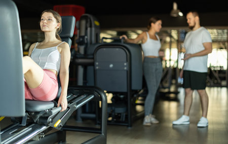 Slender athletic girl work out muscles of legs and thighs on simulator in fitness clubの写真素材