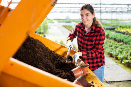 Woman farmer puts a soil in potsの写真素材