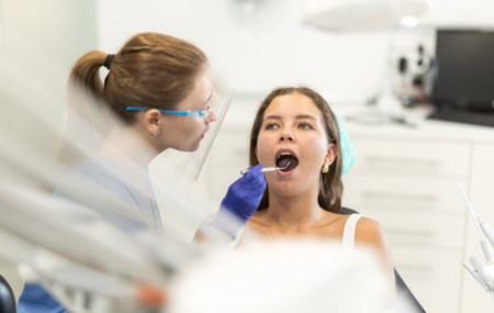 Female doctor checks young woman teeth during visit to dental clinicの写真素材