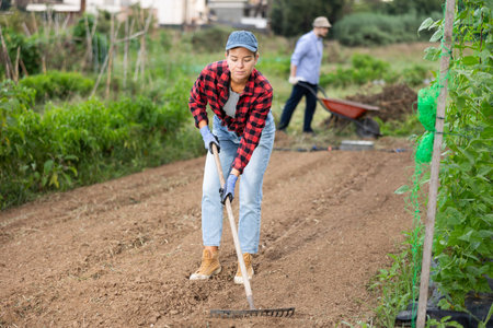 Peasant girl is working in garden with rakeの写真素材