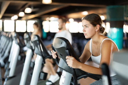 Young woman exercising on exercise bike in gymの写真素材