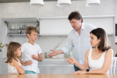 Angry parents scolding two children standing in front of themの写真素材