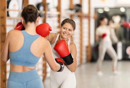 Young girl training boxing with partner during sports classes