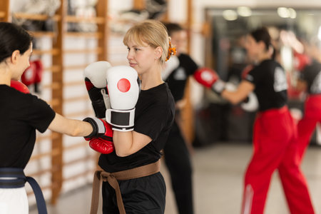Young girl training boxing with partner during sports classes