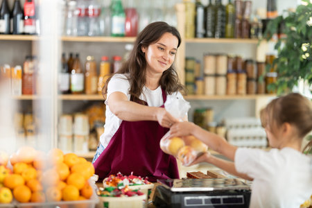 Girl buys apples. Positive female seller weighs apples on scalesの写真素材