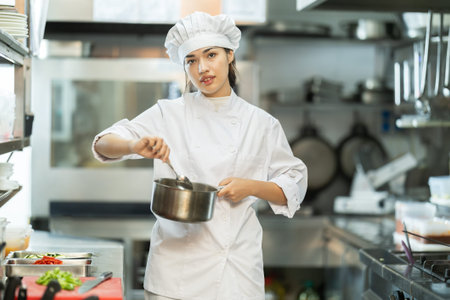 Young female cook mixing something in little saucepan