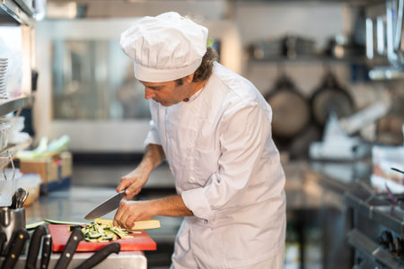Adult male chef chops ingredients for dish