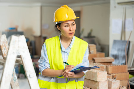 Woman making notes on indoor construction siteの写真素材