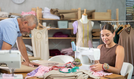 Young woman sewing male assistant drawing pattern on paperの写真素材