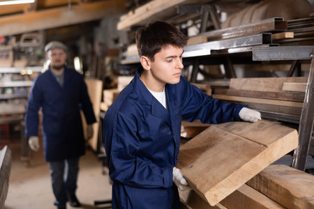Young guy takes wooden board from stackの写真素材