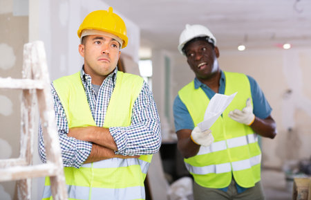 Portrait of confused man builder and angry foreman in construction site