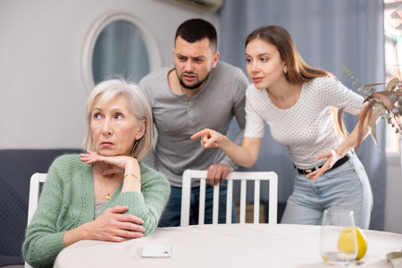 Old woman ignoring her daughter and son-in-law arguing with herの写真素材