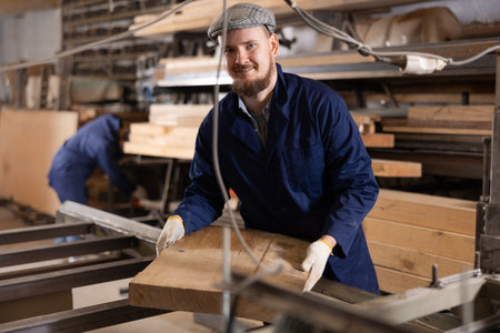 Male worker carries board from storage location to processing location. Selects planks for furniture manufactureの写真素材