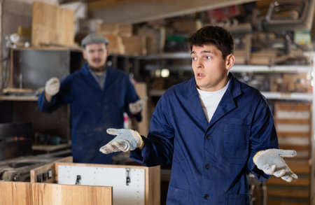 Disgruntled furniture factory owner yells at careless workerの写真素材