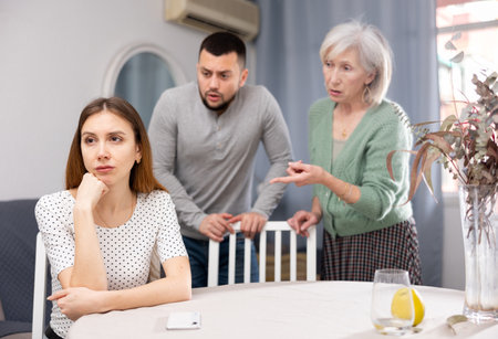 Man and mature woman scolding young womanの写真素材