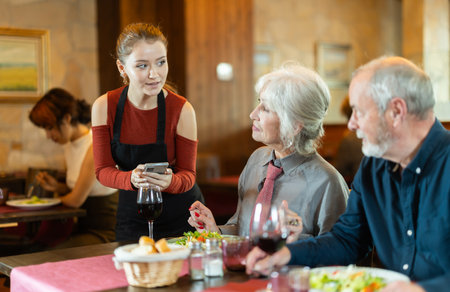 Waitress takes order from couple elderly man and womanの写真素材
