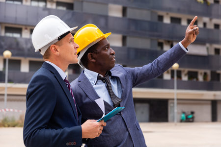 Positive architect and contractor having brief meeting on construction site