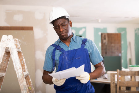 African american foreman examines documents and plans a workflow for repairs