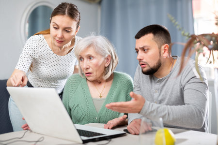 Couple teaching old woman to use laptopの写真素材