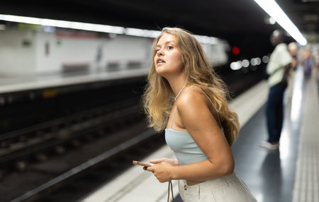 Young girl standing in platform with phone in hand
