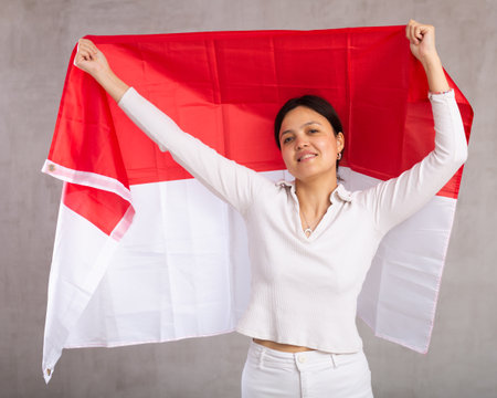 Pretty young female student holding Indonesia flag in her handsの写真素材