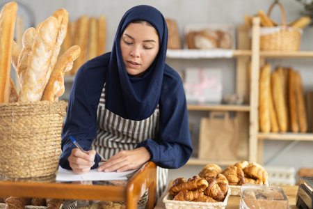 Muslim woman filling out paperwork in bakery