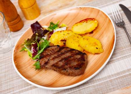 Roasted veal with potatoes fries on a ceramic plate cooked in cafeの写真素材