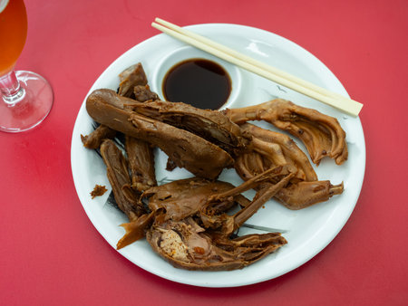 Portion of fried boiled parts of duck carcass is laid out on plate - paws, wings, head.の写真素材