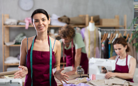 Female seamstress invites others to sew and work in sewing workshopの写真素材
