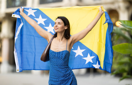 Young woman with flag of Bosnia and Herzegovina on city streetの写真素材