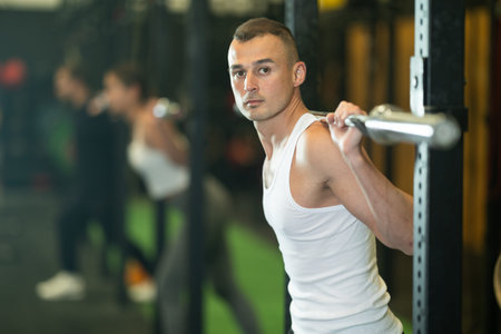 Sporty man exercising with barbell during functional training