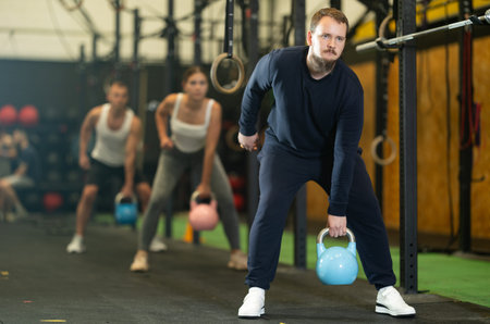 Bearded guy performing one arm kettlebell swings in gym