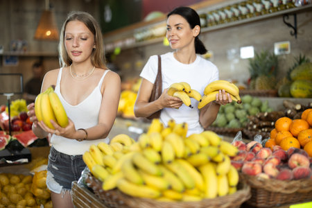 Two woman shopping in supermarket - choosing fruit bananasの写真素材