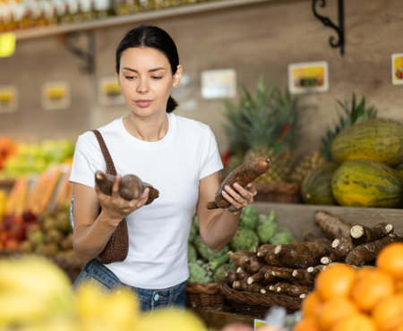 Adult woman choosing cassava at vegetable shopの写真素材