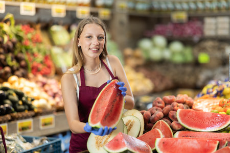 seller woman offering red watermelon in supermarketの写真素材