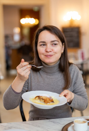 Smiling woman tasting apple strudel with coffee in Viennese cafeの写真素材