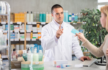 male pharmacist communicates with a client on card paymentの写真素材