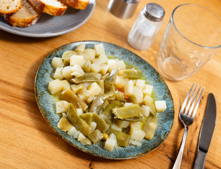 Plate contains light side dish of stewed vegetables - potatoes, green string beans, onionsの写真素材