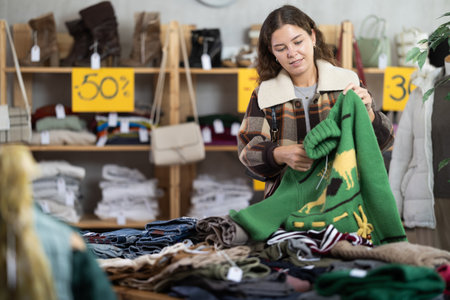 Girl chooses warm pullover, cardigan or sweater in clothing storeの写真素材