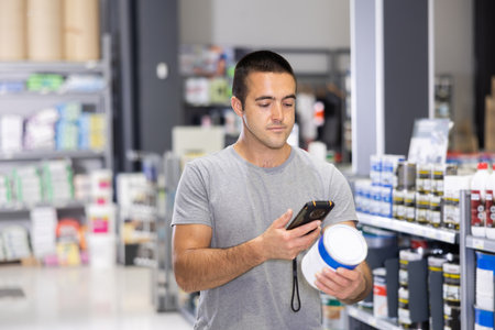 Male shopper scanning a QR code using a mobile phone in hardware storeの写真素材