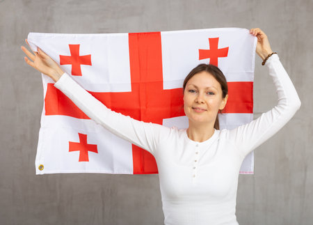 Happy young woman holding flag of Georgia against unicoloured backgroundの写真素材
