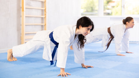 Two women doing stretching before karate or judo trainingの写真素材